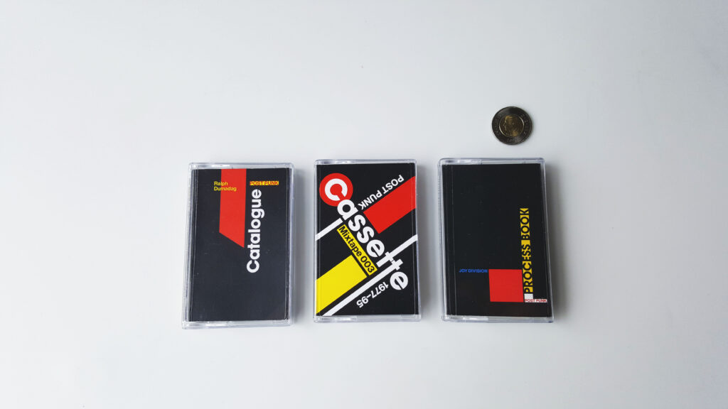 Picture of three cassette sized booklets arranged in a row with a coin for scale